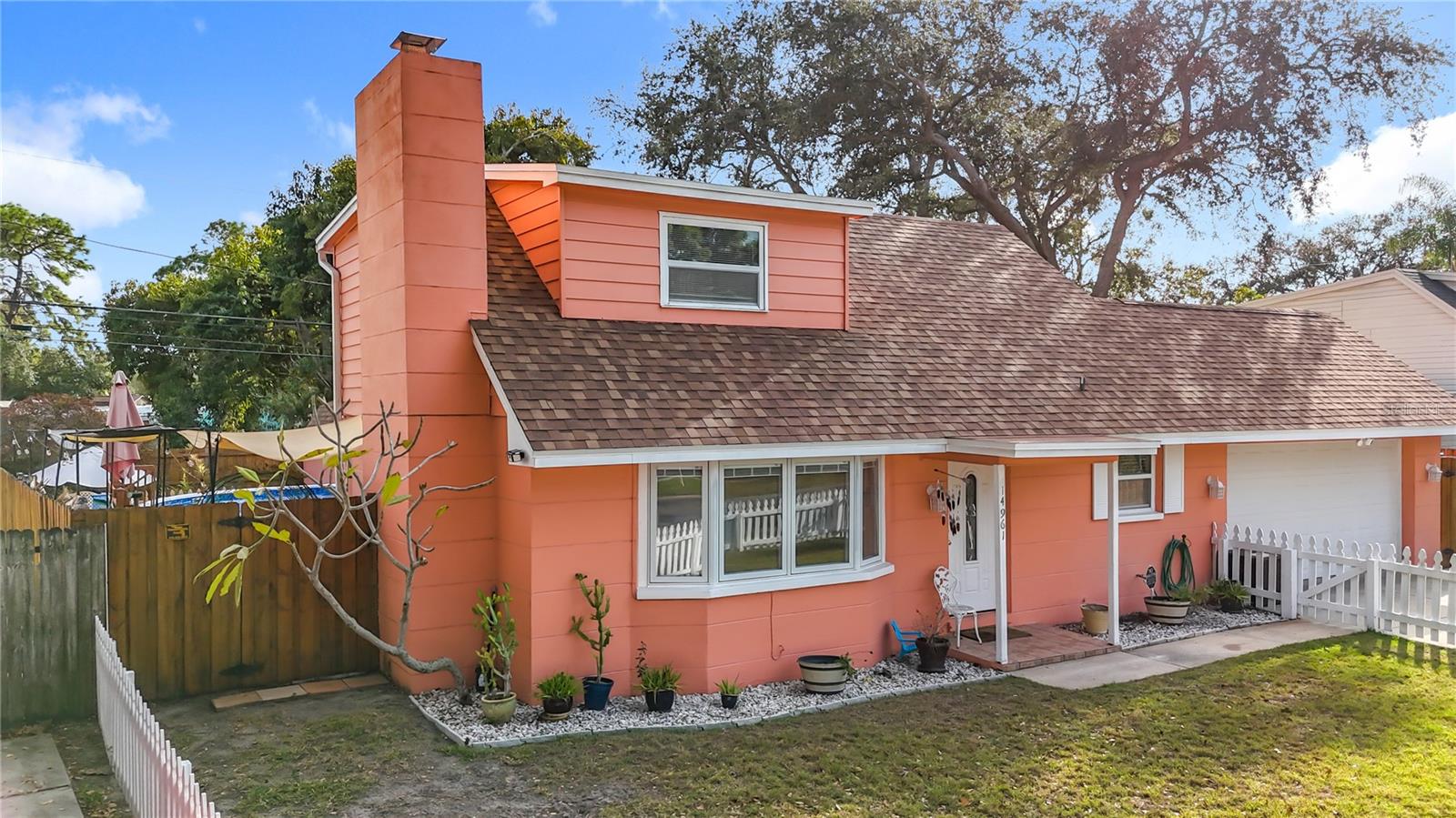 This is the East side of the front of the house. Yes, that is a working chimney for the wood burning fireplace in the living room. The area behind the fence houses a well thought out planting/garden area. The upper level in this picture is one of the bedrooms.
