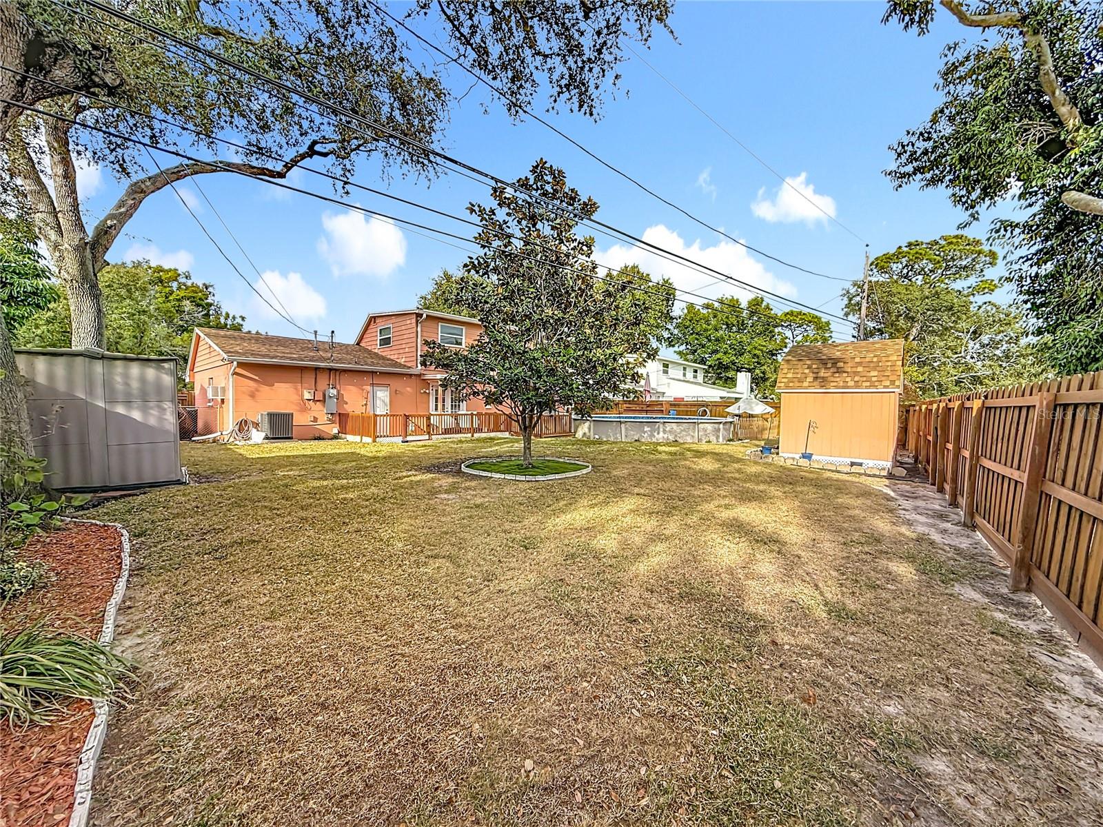 Long view of the back yard. The white door leads to the garage and just next to that door is a convenient outdoor shower:-)