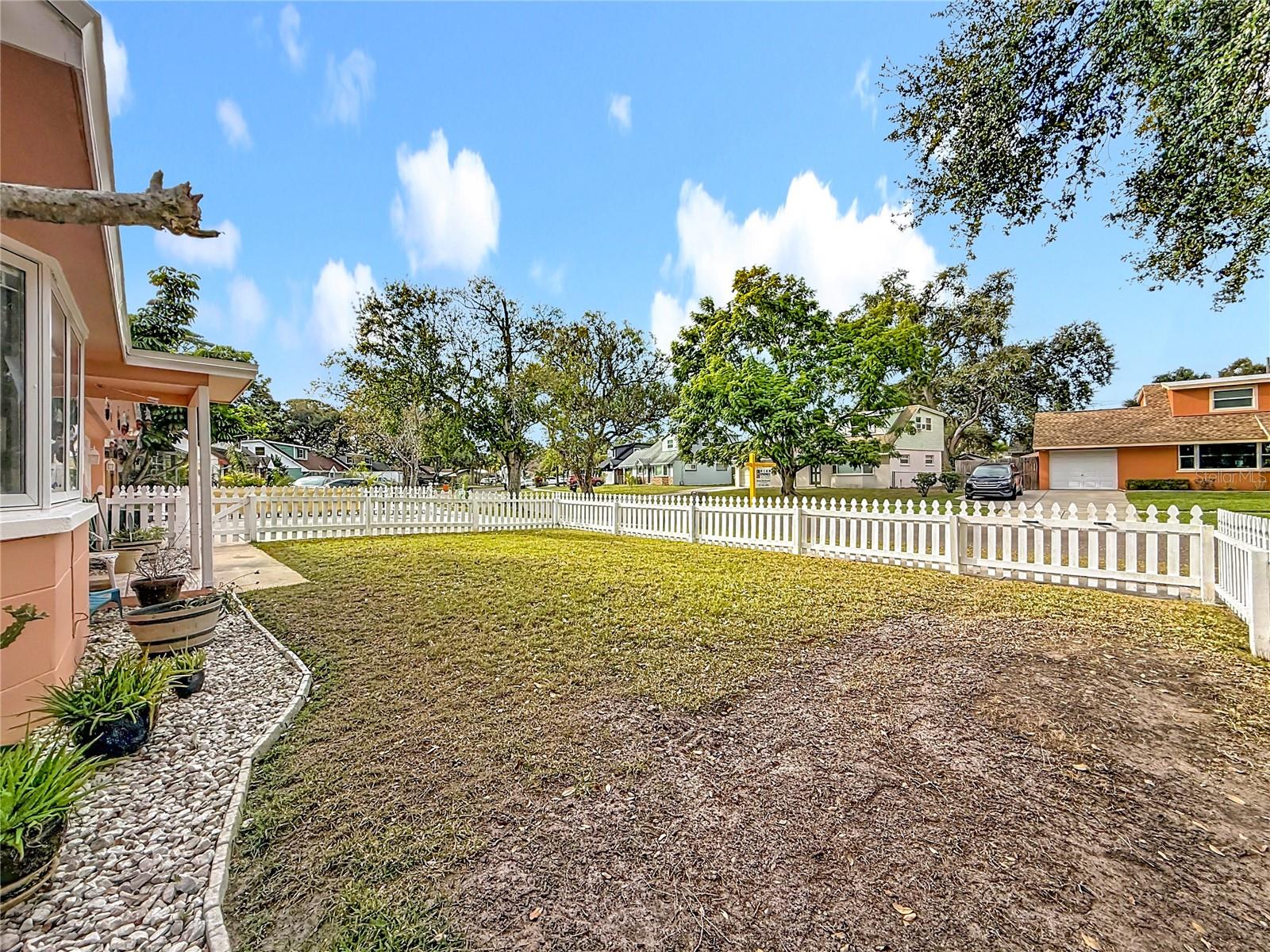 This view is from the east side of the house towards the front yard. If you notice the grass is a little different in one section, to the right, that is because you can actually MOVE part of the picket fence & park ANOTHER vehicle here , if you need.