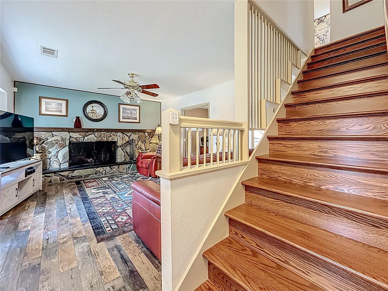 The front door is to your left. Your back is to one of the entrances into the kitchen. Those are solid wood: Red Cherry. The banisters are, also. View into the living room. New LVP flooring. Wood Burning fireplace. It has been re-bricked inside. Large stone wall with wide hearth. The opening off the living room is a set of French doors leading into the 4th bedroom. (currently being used as an office). While you can't see it from this side, under these stairs (on the other side) is a substantial closet.