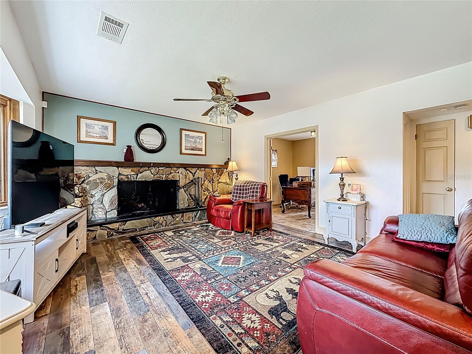 Slightly closer view of the living room. From this vantage point, you will see the 4th bedroom (currently being used as an office). The opening to the right, next to this red couch, leads to: a small hall closet, the updated half-bath and then the dining room and into the kitchen.