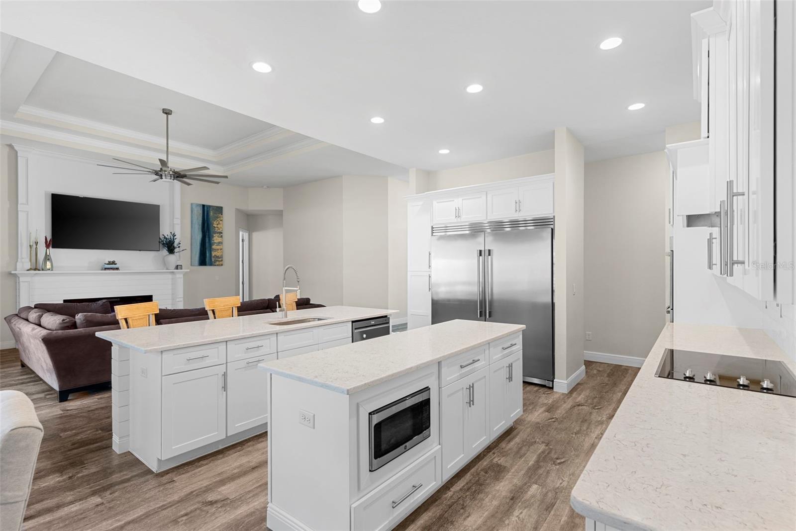 Bar seating at the island and a nearby dining nook with designer lighting offer multiple options for casual or formal meals.