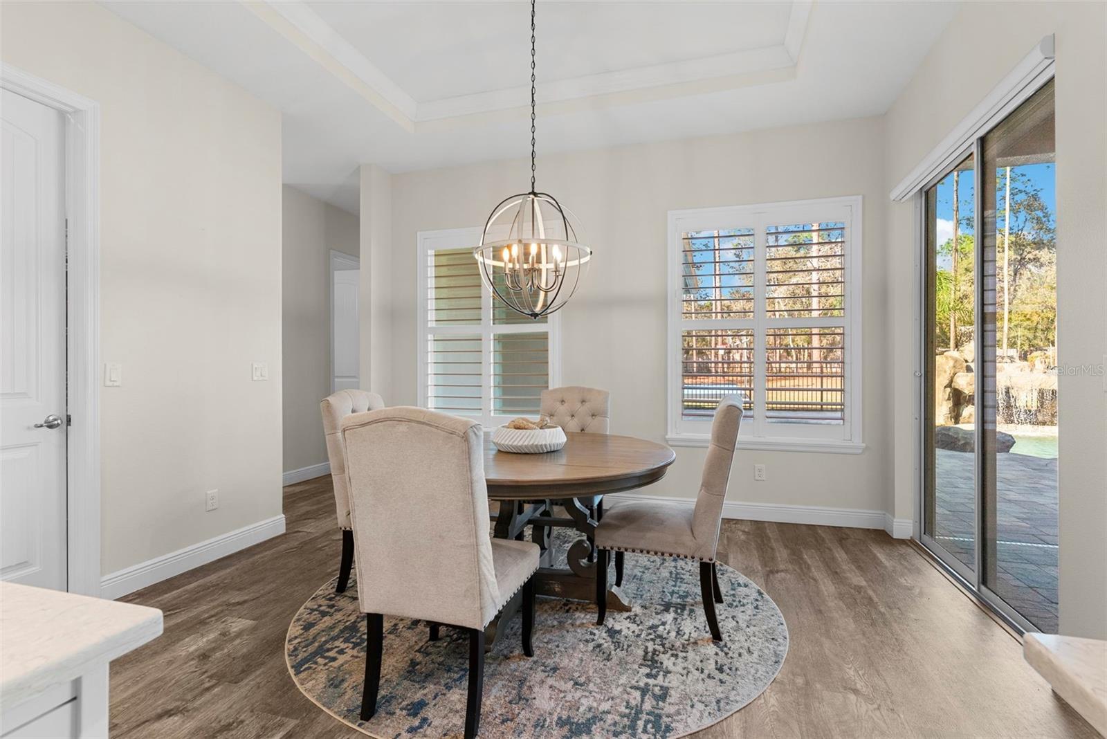 Recessed lighting and large windows illuminate the kitchen and adjacent dining space, emphasizing the home's open and airy design