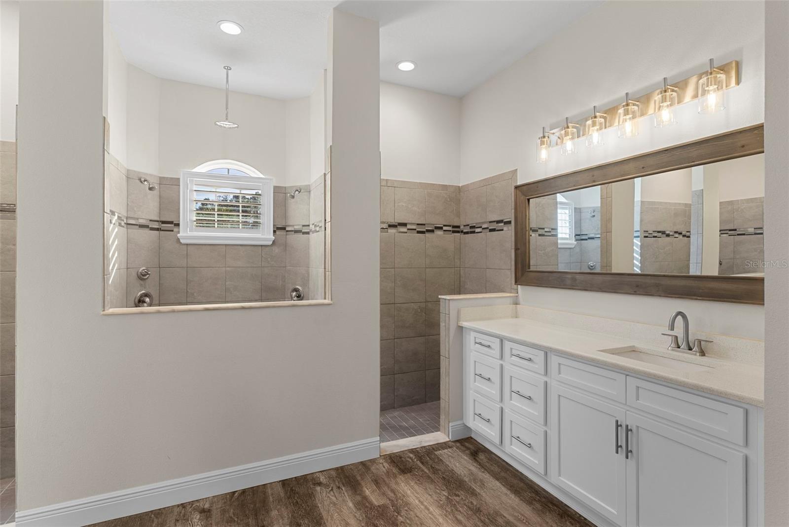 **Primary Bathroom** – A spa-inspired retreat featuring dual vanities, quartz countertops, and an oversized walk-in shower with double showerheads and a rainfall fixture