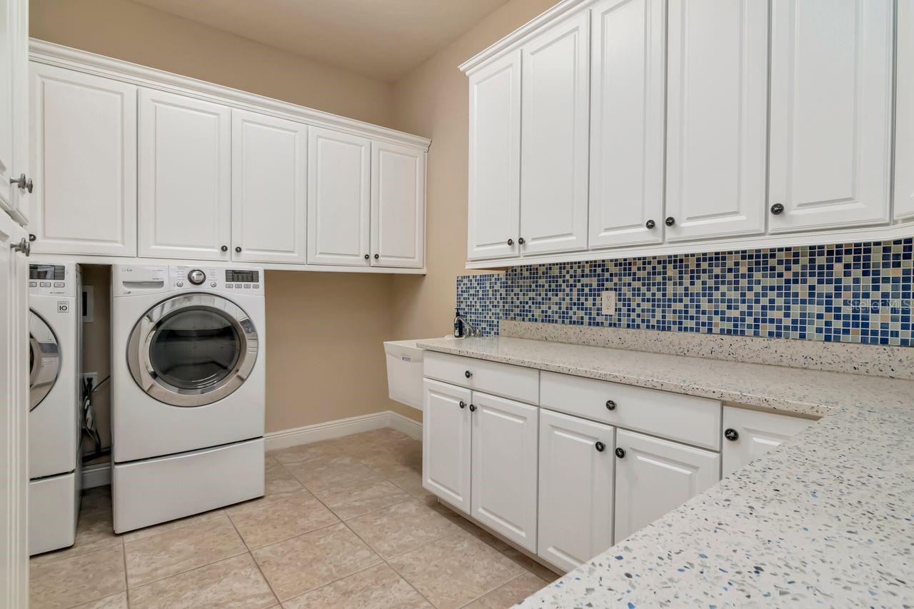 Functional Laundry Room with Granite Surfaces and Generous Cabinetry