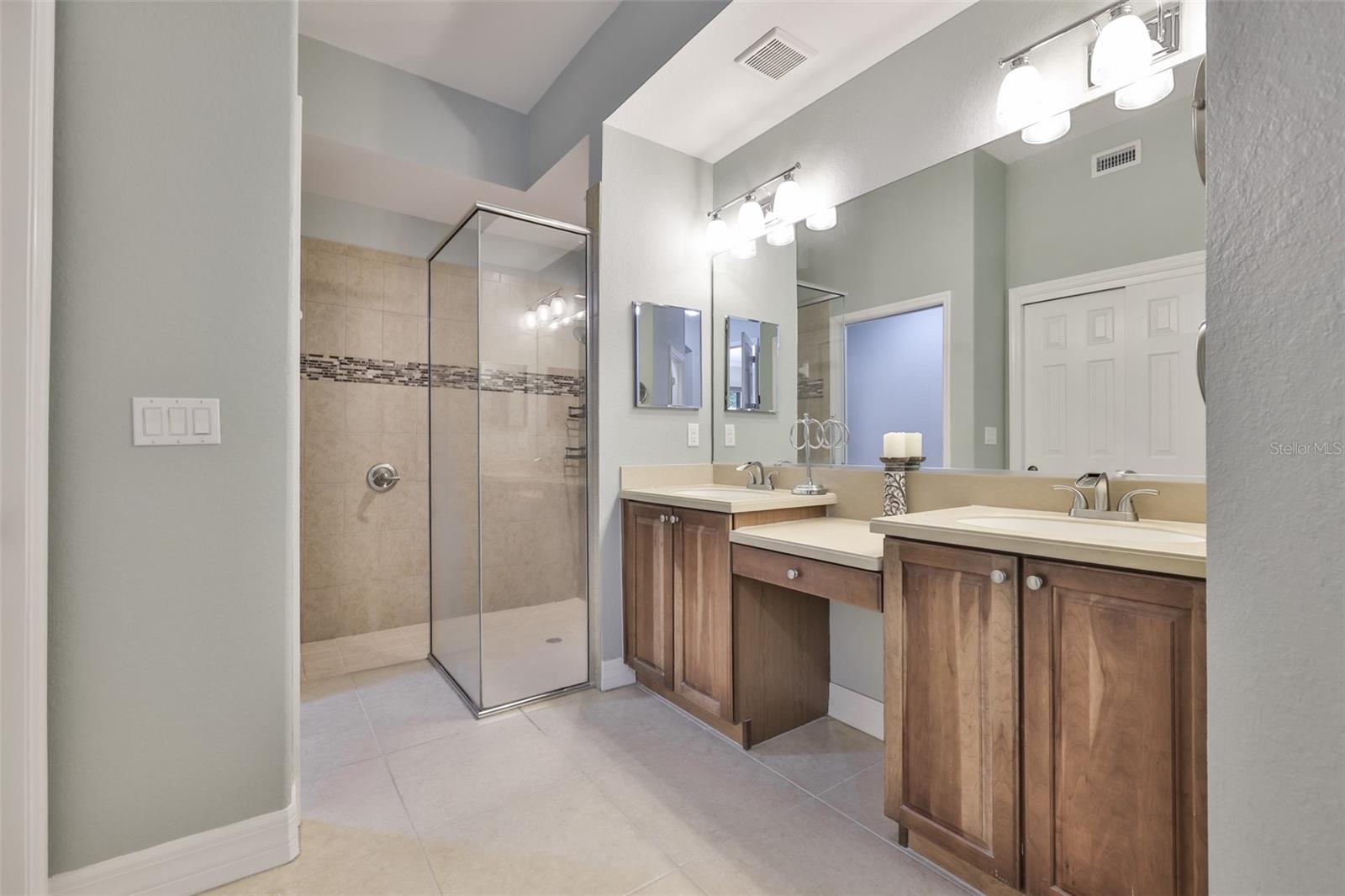 Lovely modern and bright this ensuite bathroom has dual sinks, high-end medicine cabinets, walk in shower with dual shower heads. The water closet is a private with a door.