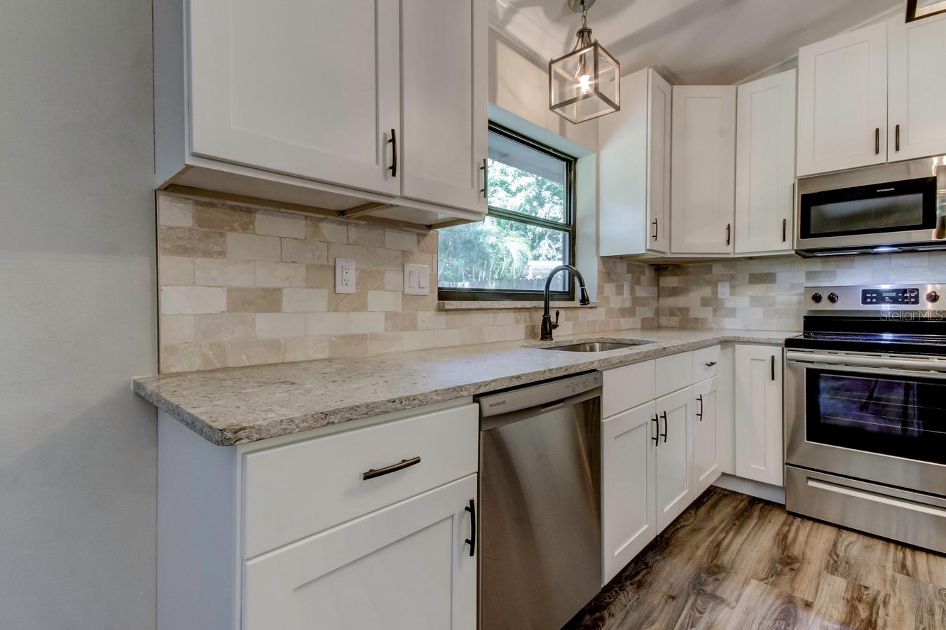 Kitchen with stainless steel dishwasher, range, and microwave