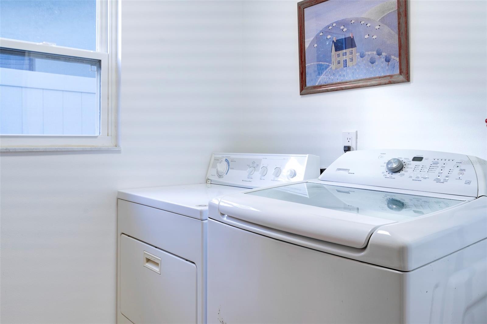 Large interior laundry room with folding table across from the washer/dryer.