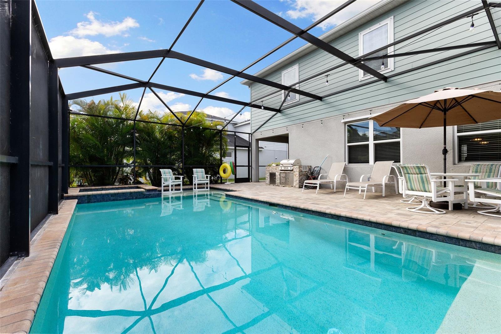 Screened lania with satwater pool and spa surrounded by lush palms and fruit-bearing avocado and papaya trees