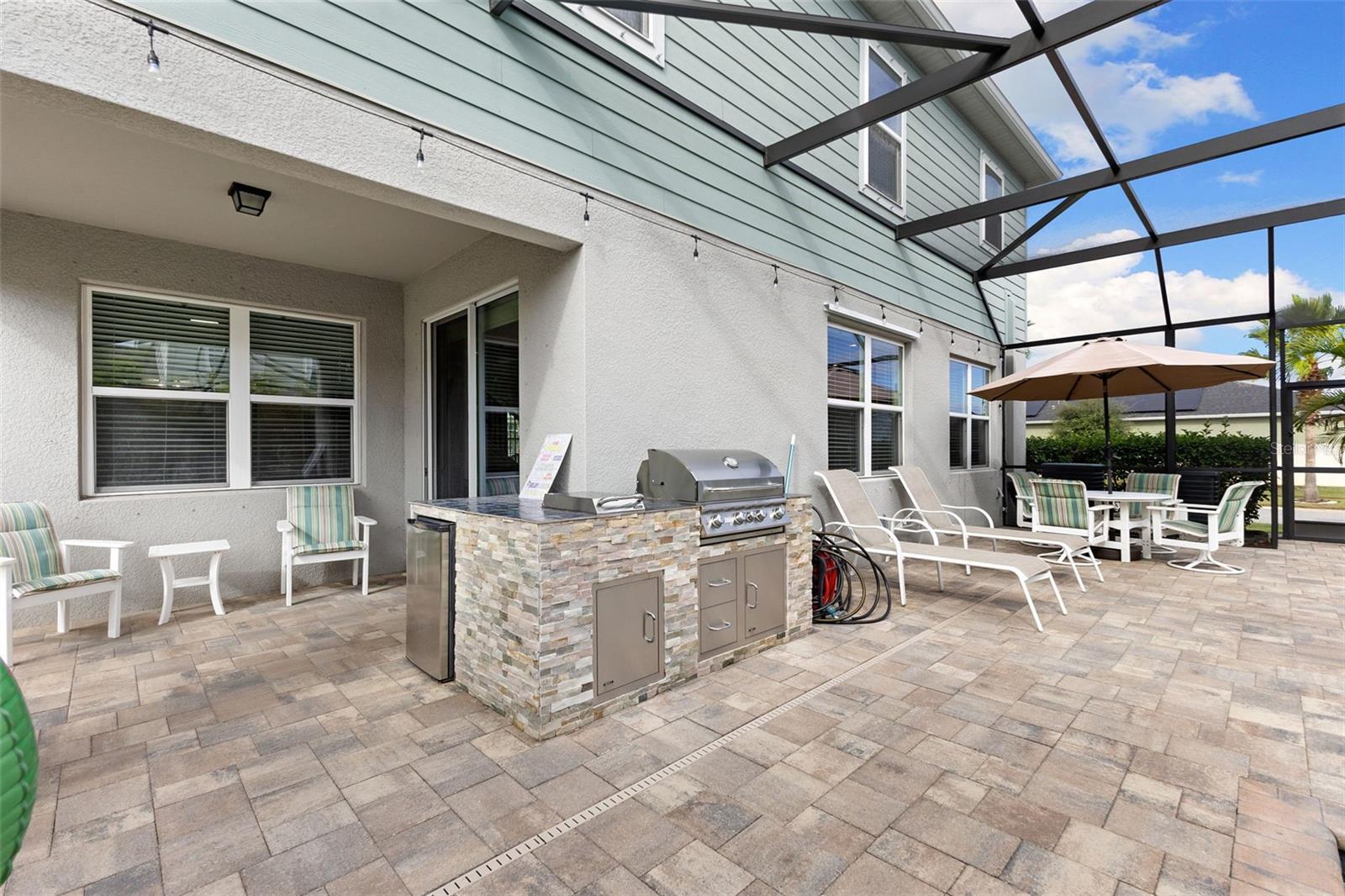 Stone-faced outdoor kitchen equipped with grill, burner, refrigerator and storage