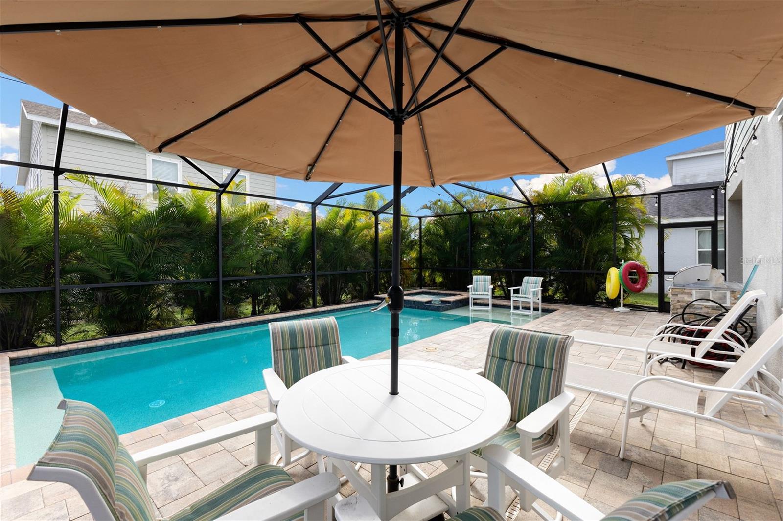 Screened lania with saltwater pool and spa surrounded by lush palms and fruit-bearing avocado and papaya trees