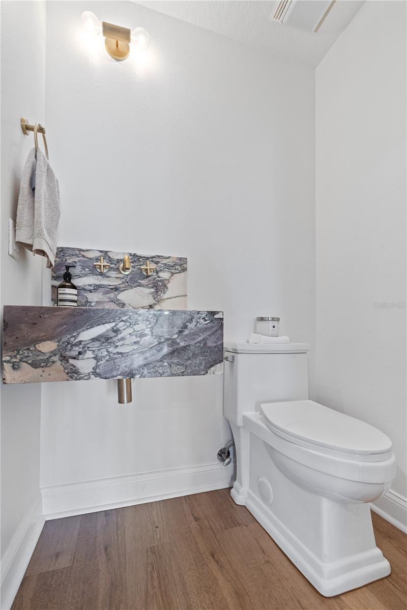 Floating hand sink in guest bath with brass fixtures