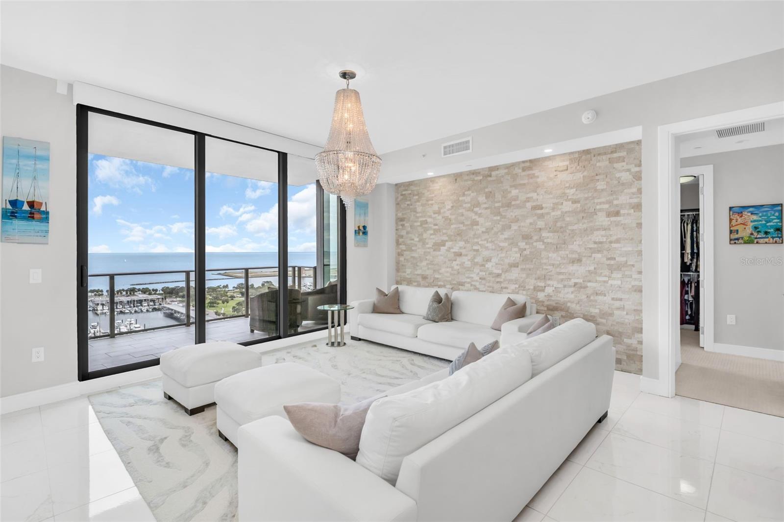 Large entertaining living room with custom stone designed wall, chandelier and gorgeous views of Tampa Bay