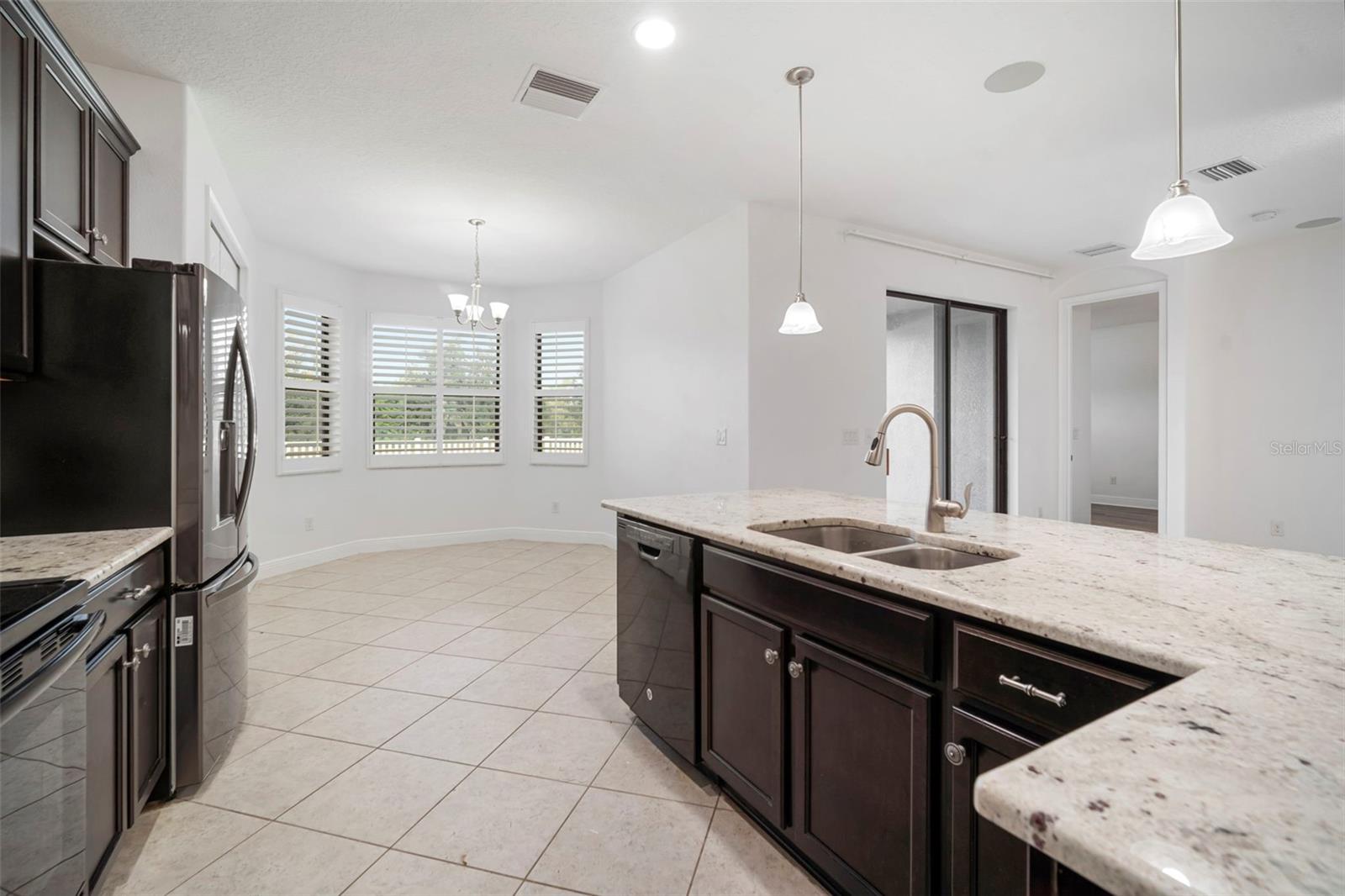 Kitchen looking into breakfast nook with large bay windows.
