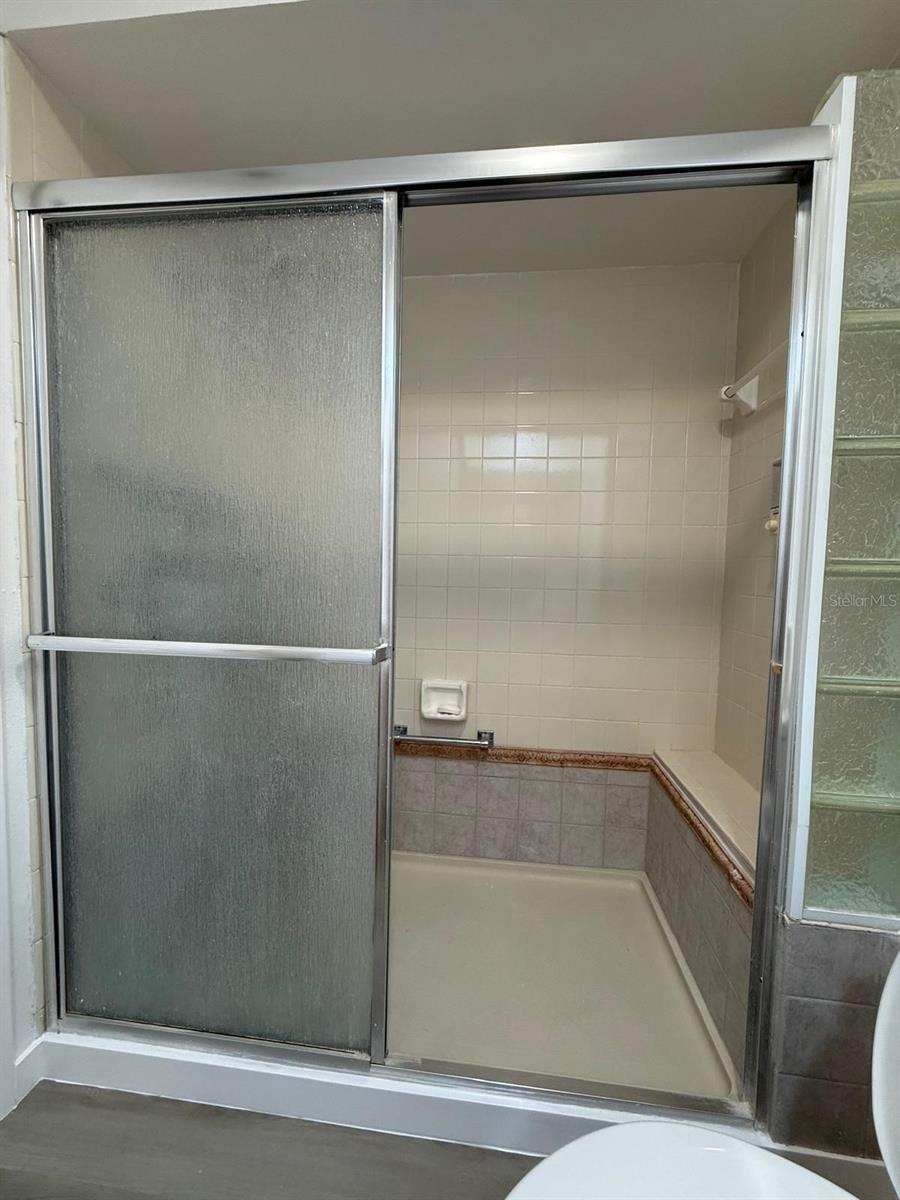 Spacious walk-in shower in full bath with bench seating.