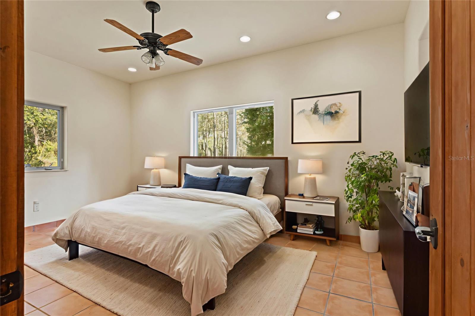 Bright and inviting, this 2nd guest bedroom features terracotta tile flooring, wooded views, and access to a Jack and Jill bath, perfect for guests or additional household members.