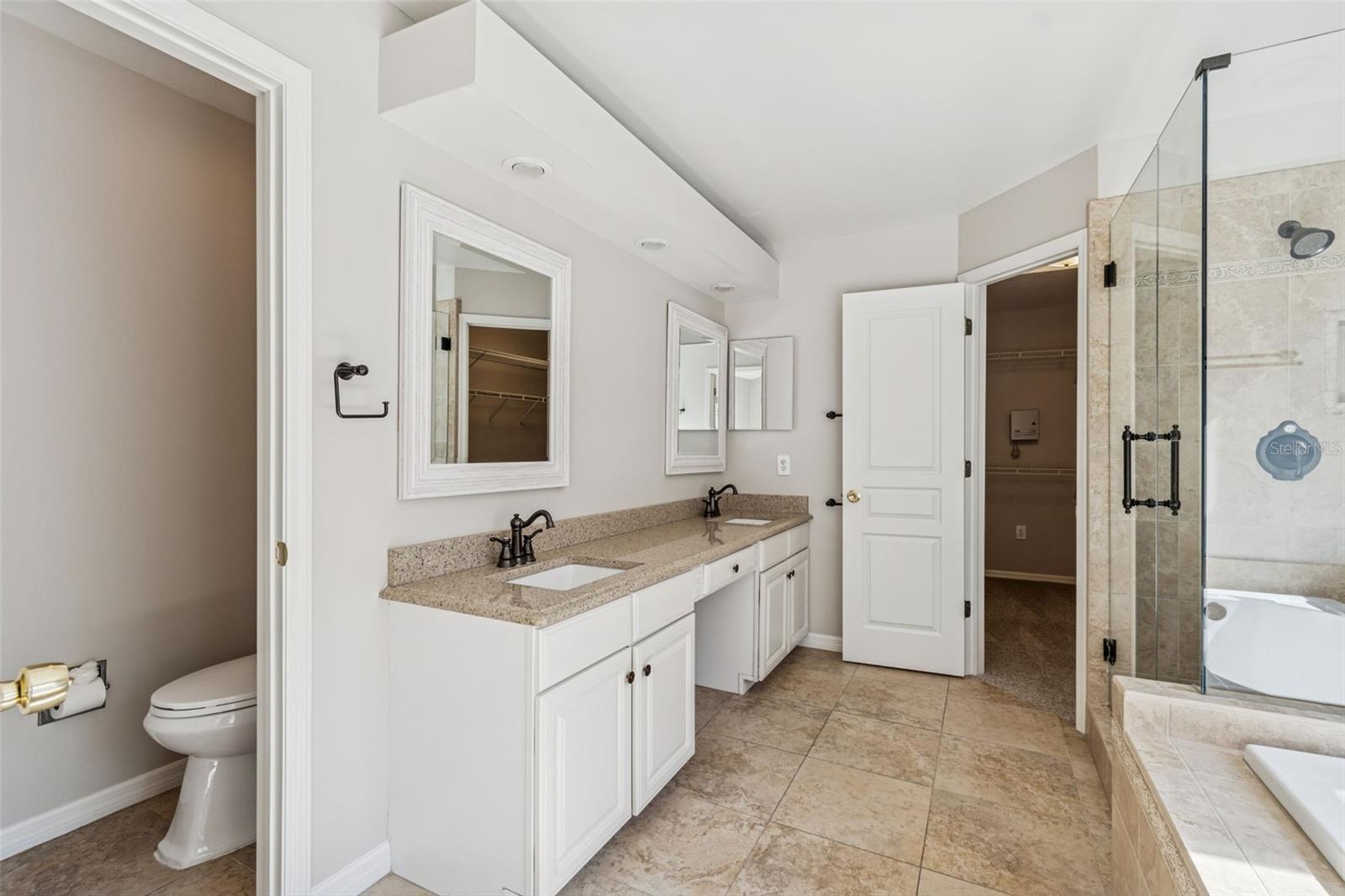 Primary bath with granite counters, dual sinks, and renovated shower and bath