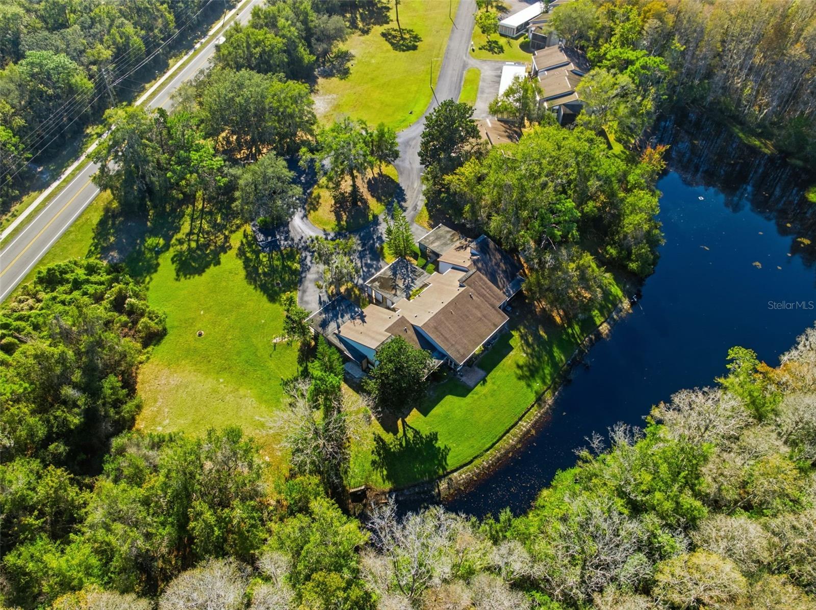 Beautiful aerial view showcasing the home’s peaceful peninsula-style lot with lush greenery and a serene waterfront backdrop.