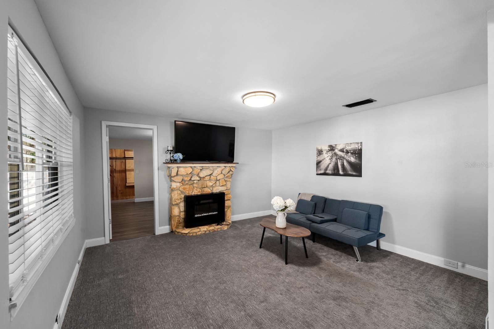 The living room has a stone electric fireplace, fresh paint, new lighting, new window blinds, updated 5-1/2' baseboards, and 18-month old carpet.