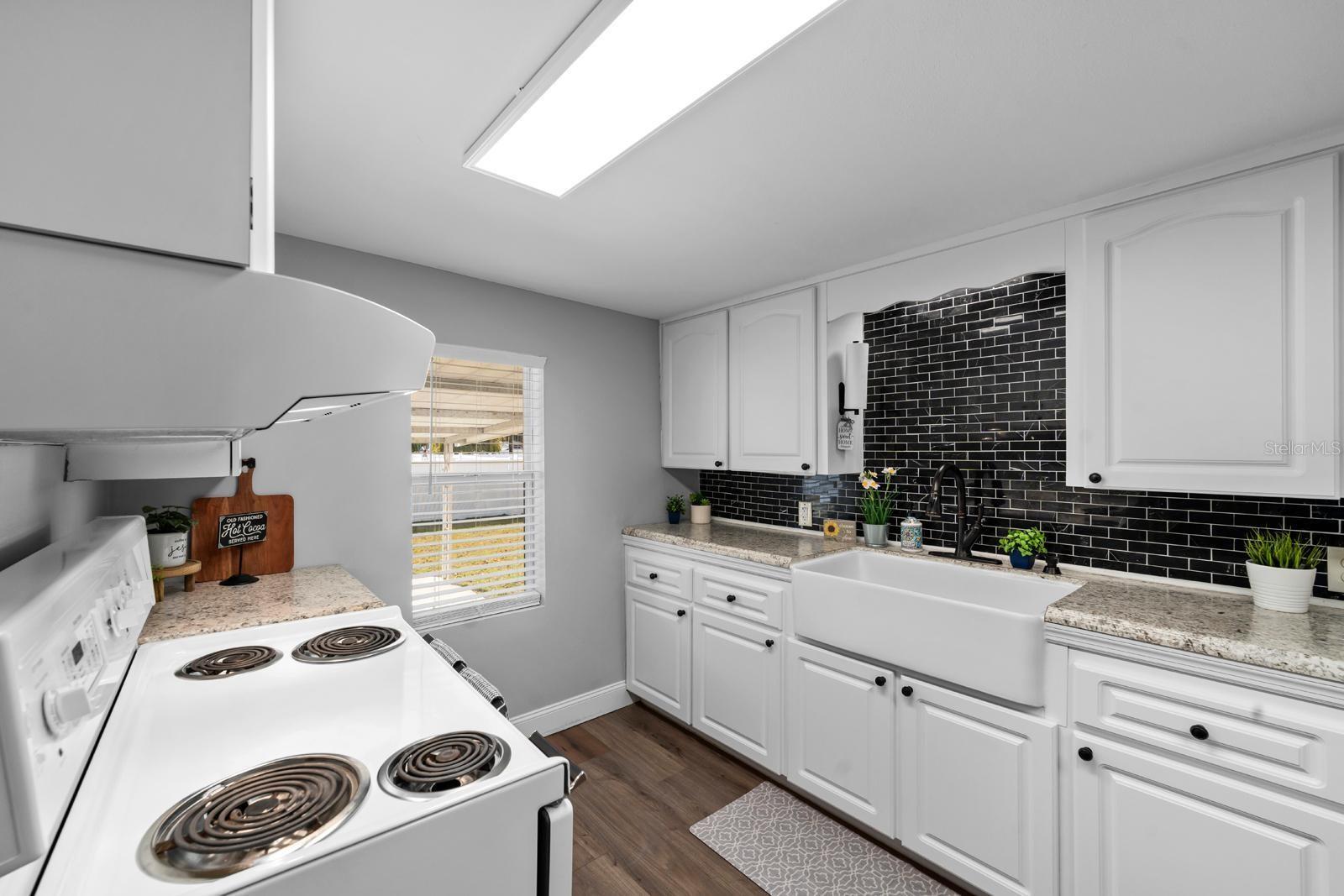 The updated kitchen features a beautiful farm sink, newer cabinets and countertops, newer appliances, the extra large range features a second oven, a range hood, new lighting, over-the-sink lighting, an updated faucet, and backsplash.