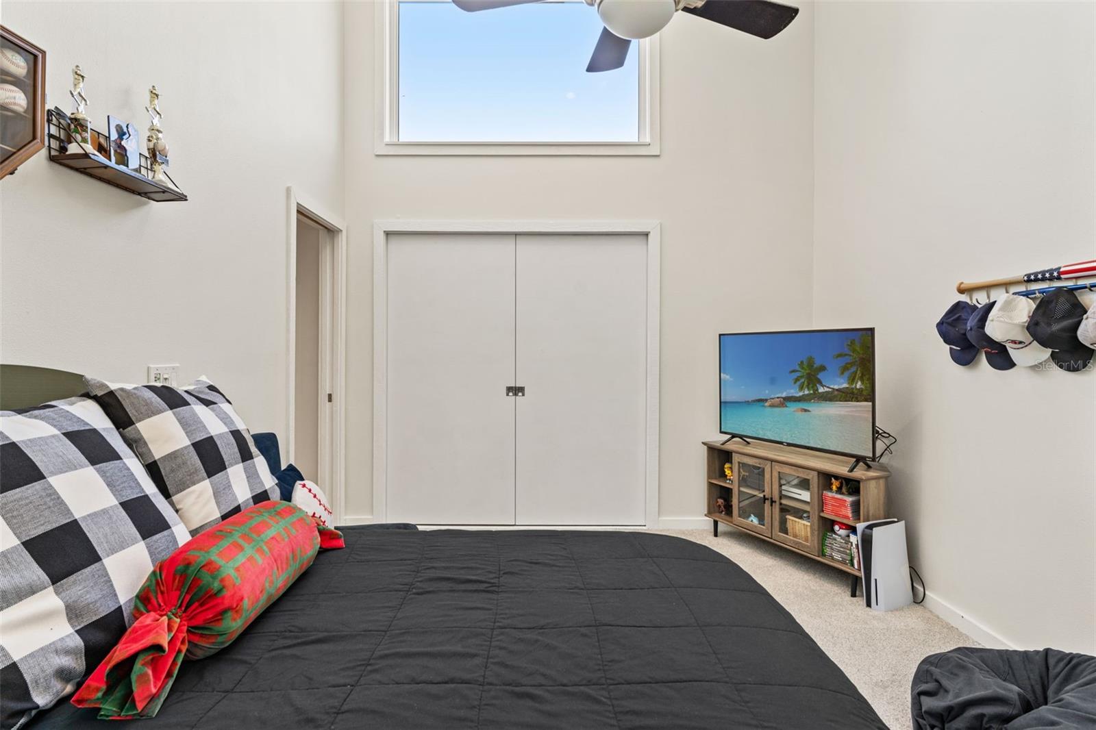 Loft bedroom featuring pocket doors for privacy, neutral carpeting, and natural light from the upper window.