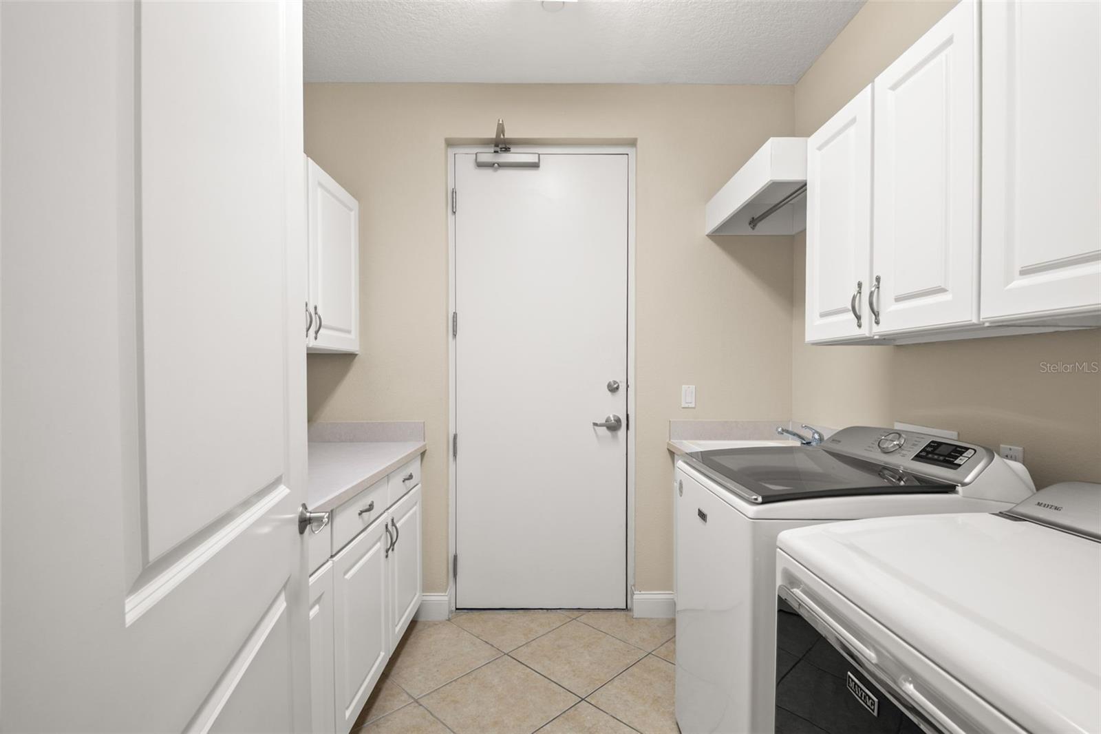 Large utility room with lots of storage, hanging space and utility sink.