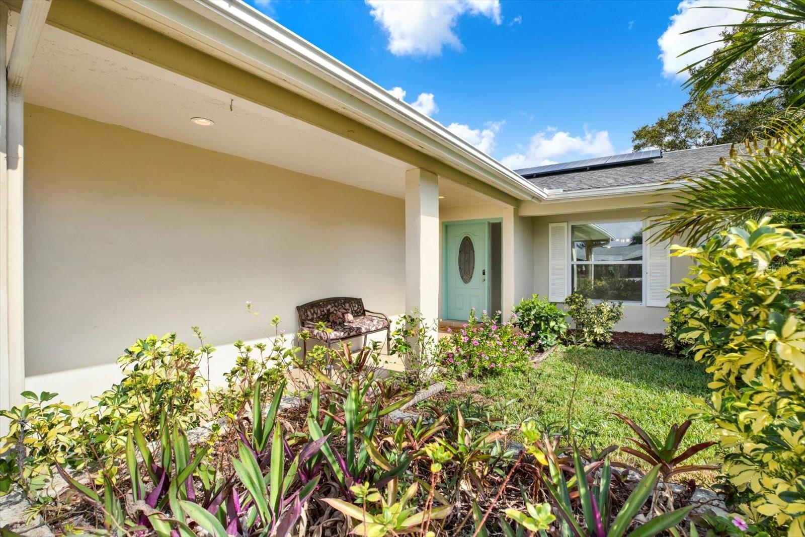 Native landscaping surrounds the recently paved front door porch and entry