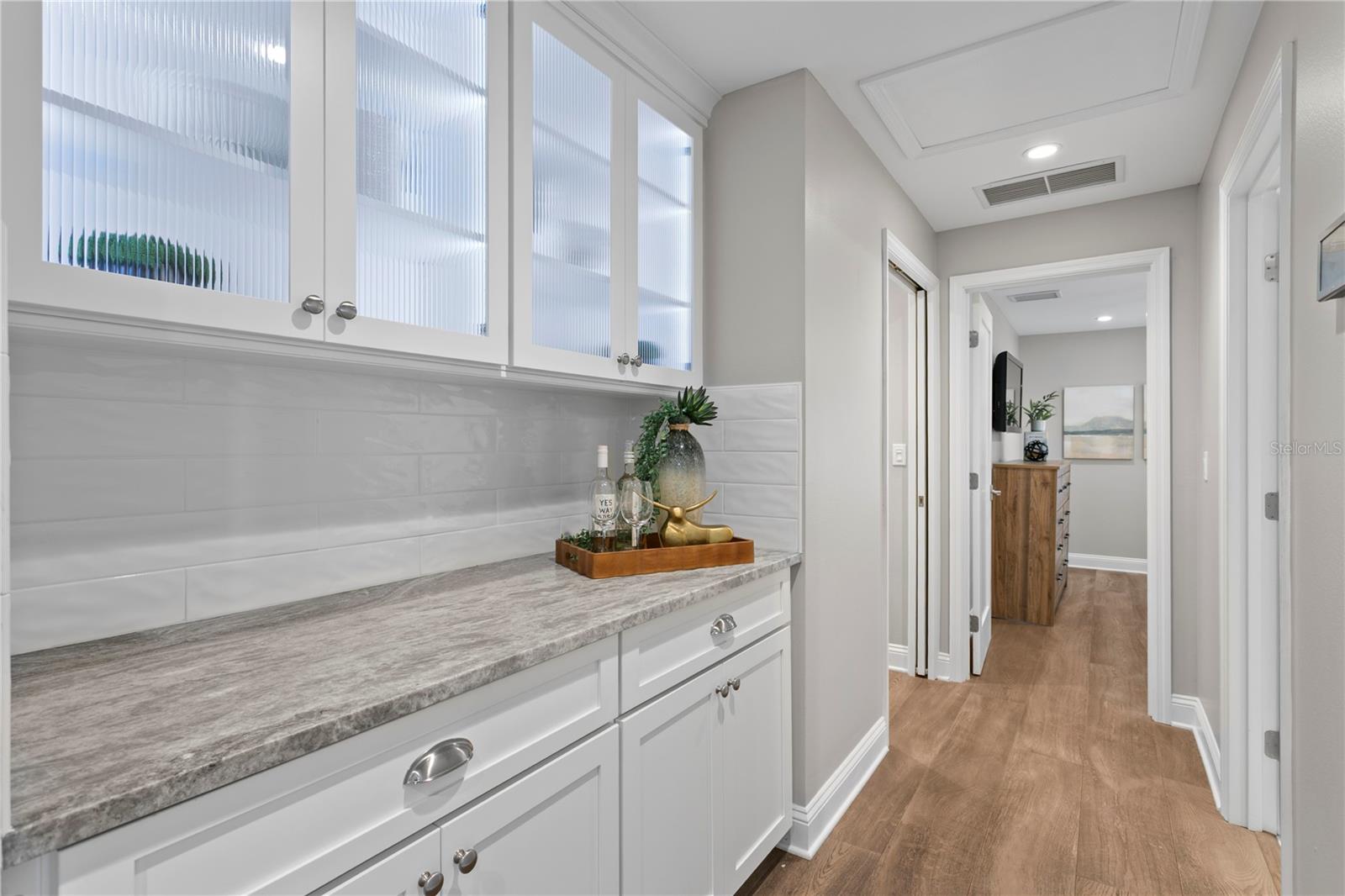 Butler's pantry with more storage, interior and under cabinet lighting connects 2 bedrooms to entertaining area