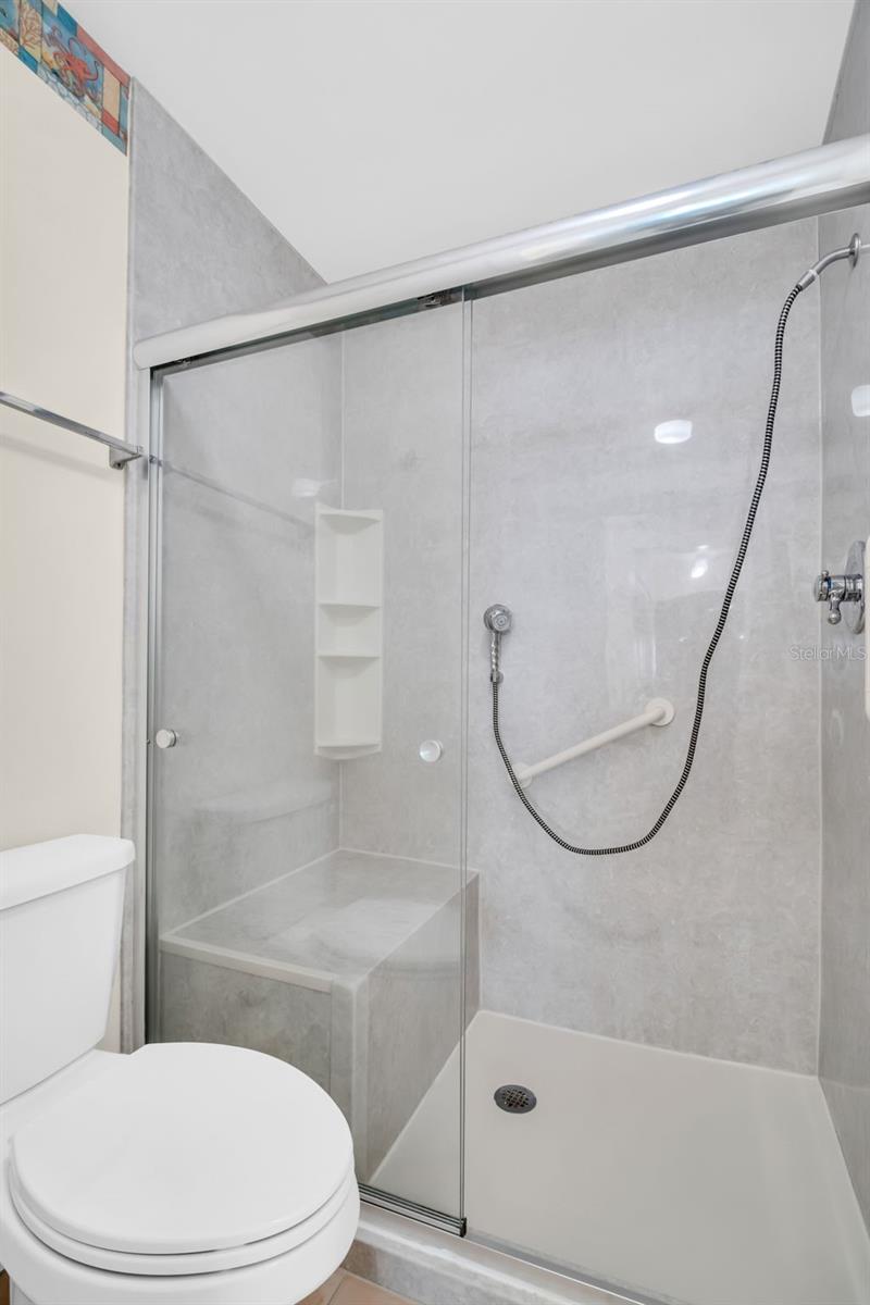 Updated en-suite walk-in shower with grab bar for safety and large built-in shower bench~