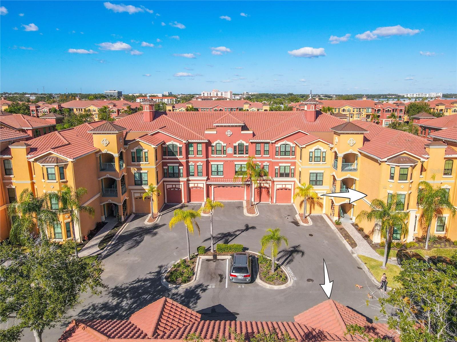 A vibrant Mediterranean-style enclave unfolds beneath blue skies, where palm-lined courtyards and elegant façades set the stage for resort-inspired living at The Grand Bellagio.