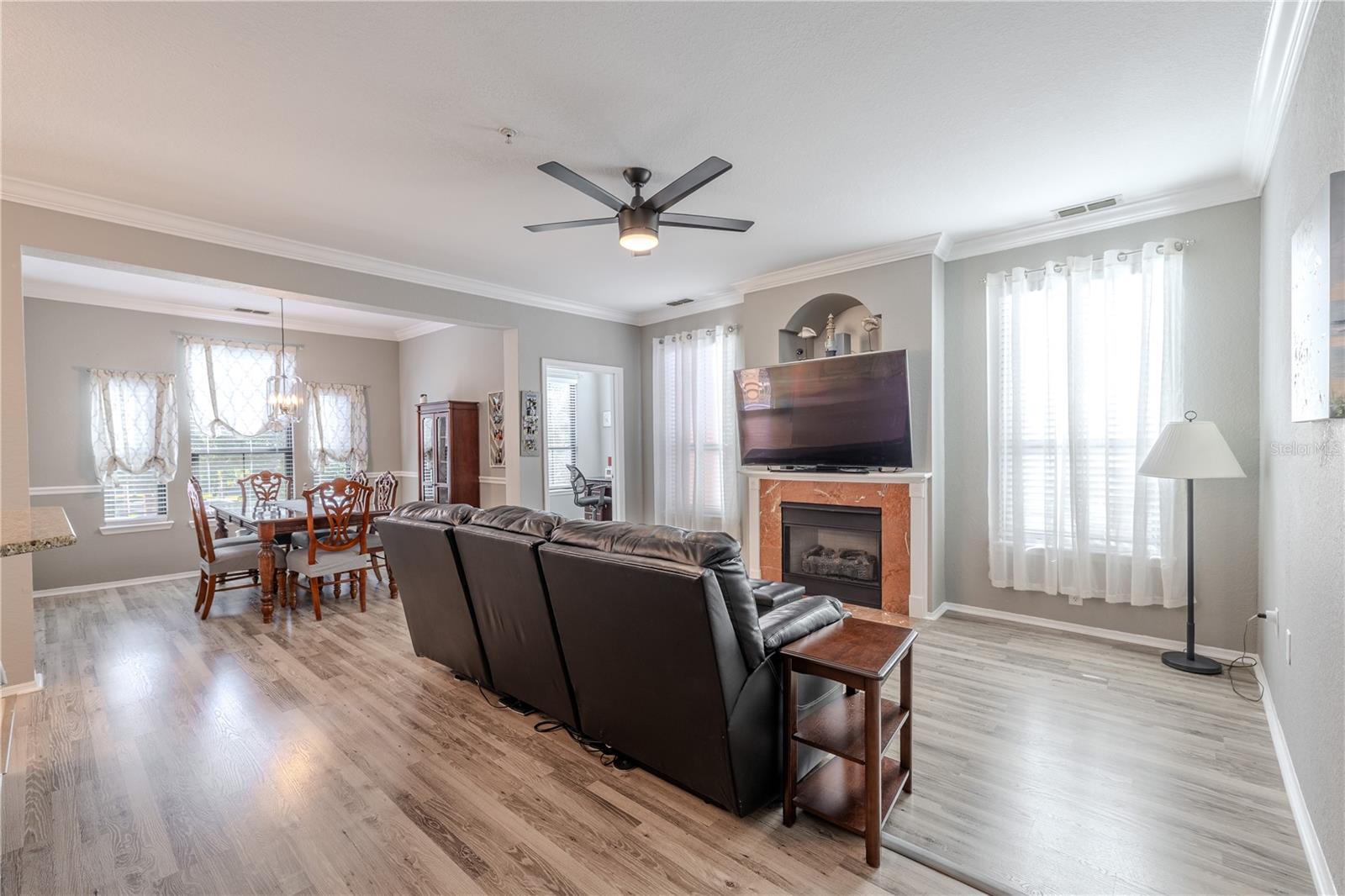 An elegant dining room features crown molding, chair rail detailing, wide-plank laminate flooring, and a modern pendant light, creating a refined space perfect for hosting gatherings and formal meals.