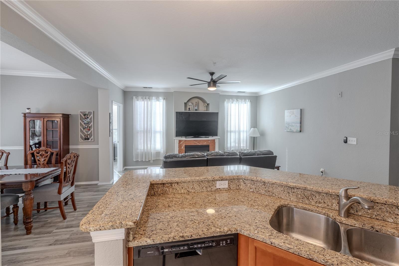 This view highlights the spacious living area with modern ceiling fan, neutral tones, and seamless sightlines into the kitchen, emphasizing the open-concept layout ideal for everyday living and entertaining.