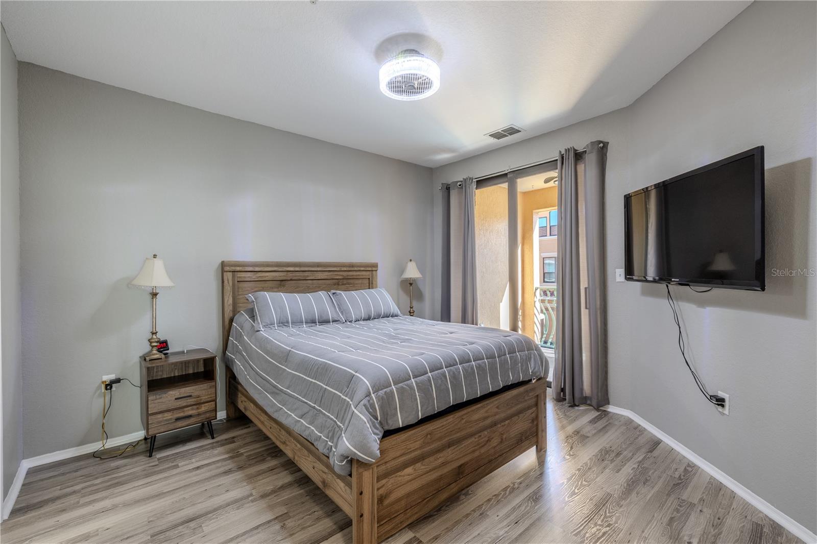 Sunlit balcony view overlooking palm-lined courtyards and Mediterranean-style architecture, offering a serene vantage point with open skies and gentle neighborhood activity below.