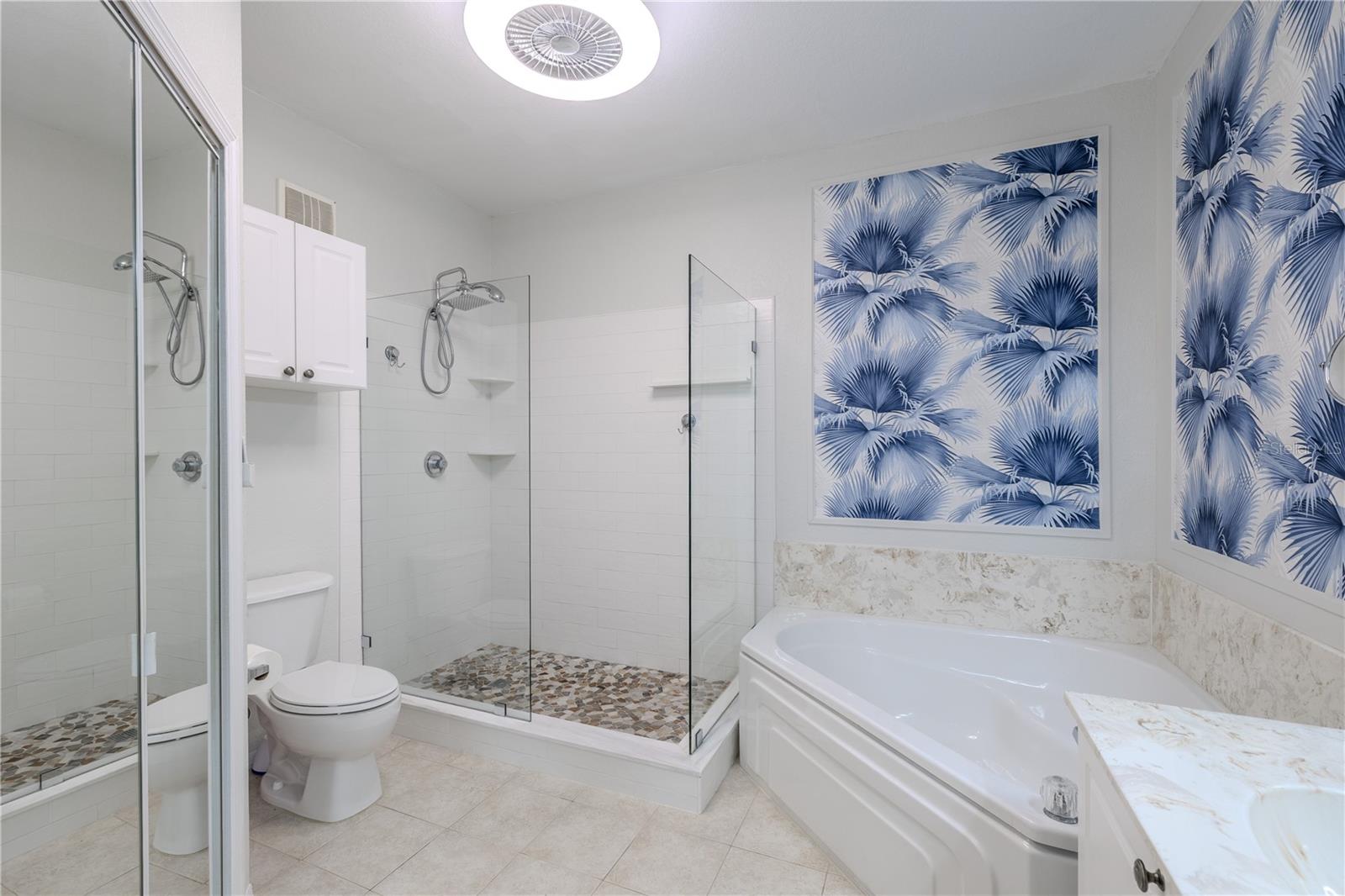 This angle showcases the seamless connection between the spa-style glass-enclosed shower and the spacious walk-in closet, highlighting exceptional storage, custom shelving, and a thoughtfully designed primary suite layout.
