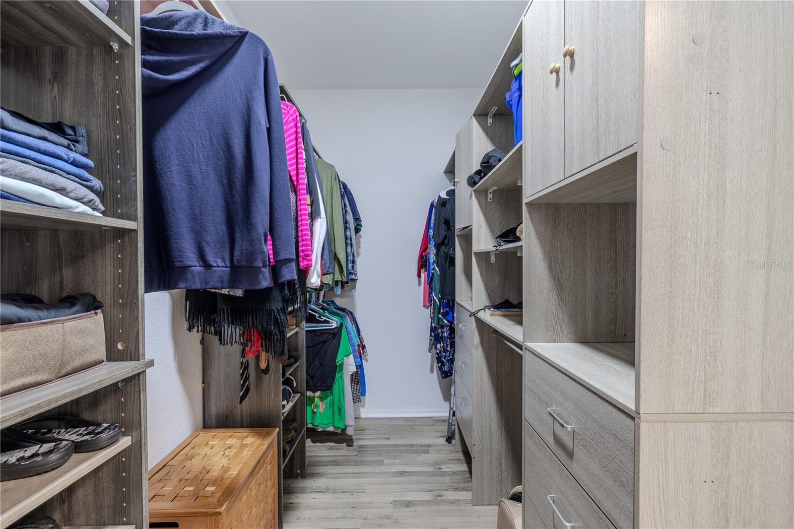 This view highlights the convenient layout of the primary suite, with the bedroom flowing into a well-appointed en-suite bath that seamlessly connects to an expansive walk-in closet with custom shelving and abundant storage.