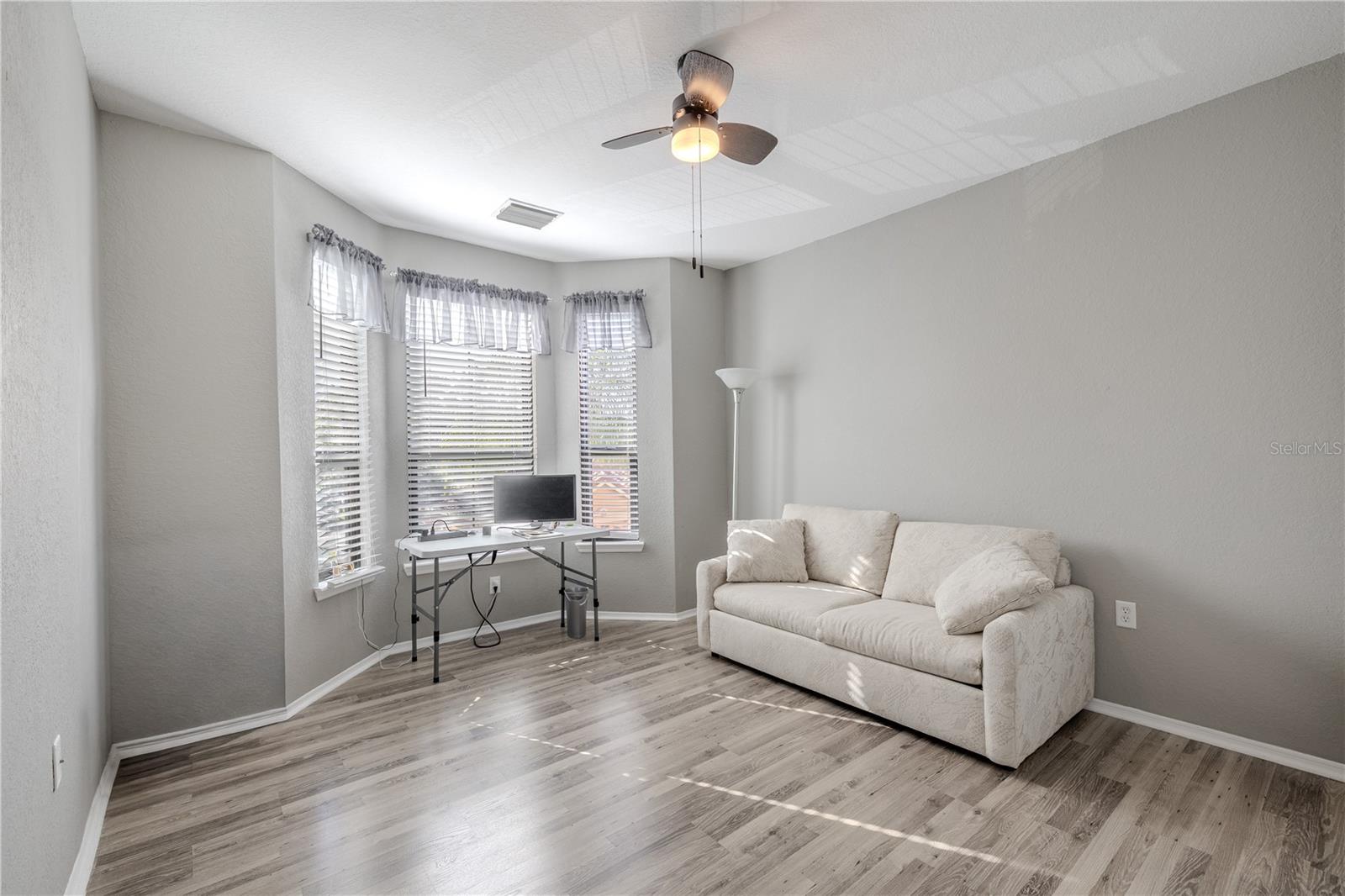This second full bathroom offers a clean, bright design with a white vanity, solid-surface countertop, ample storage, and a convenient layout located just off the hallway and adjacent to the second bedroom and den.