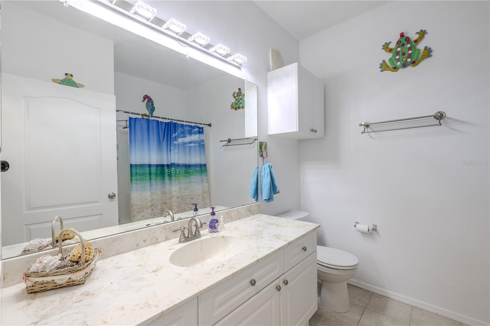 This dedicated interior laundry closet features a full-size washer and dryer, overhead cabinetry for storage, hanging space, and convenient access to the electrical panel, making everyday chores efficient and well organized.
