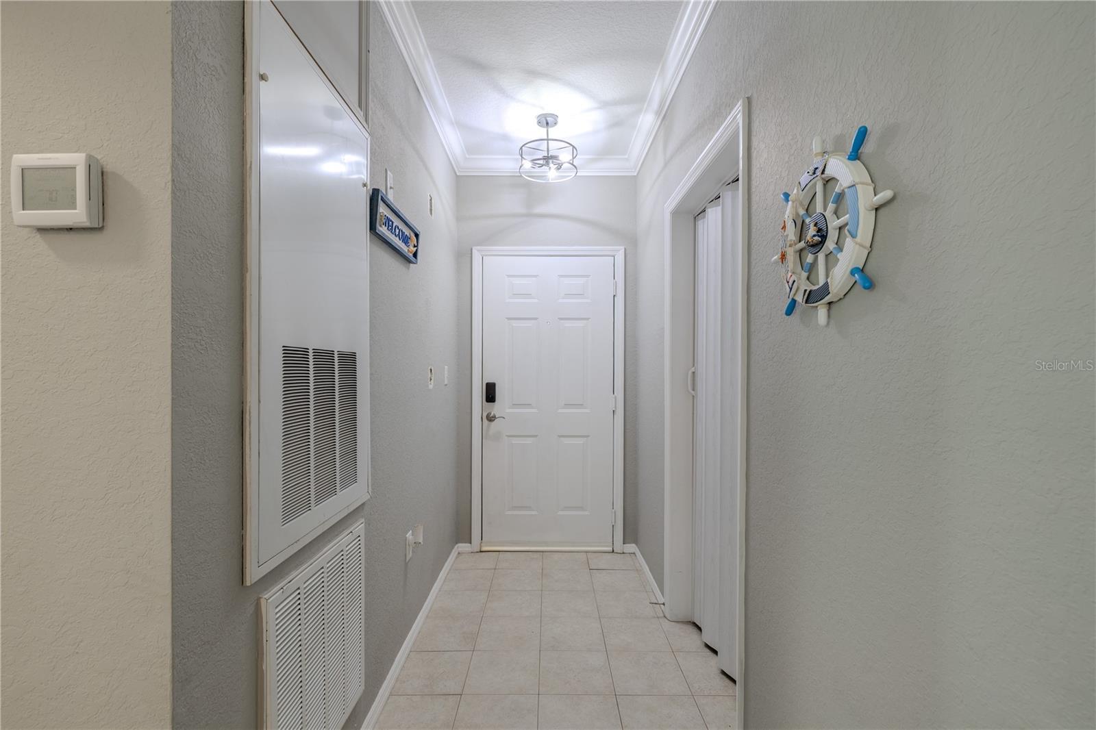 A spacious, sunlit living and dining area showcases crown molding, wide-plank flooring, a gas fireplace, and modern ceiling fan, creating an inviting open-concept layout ideal for relaxing or entertaining.