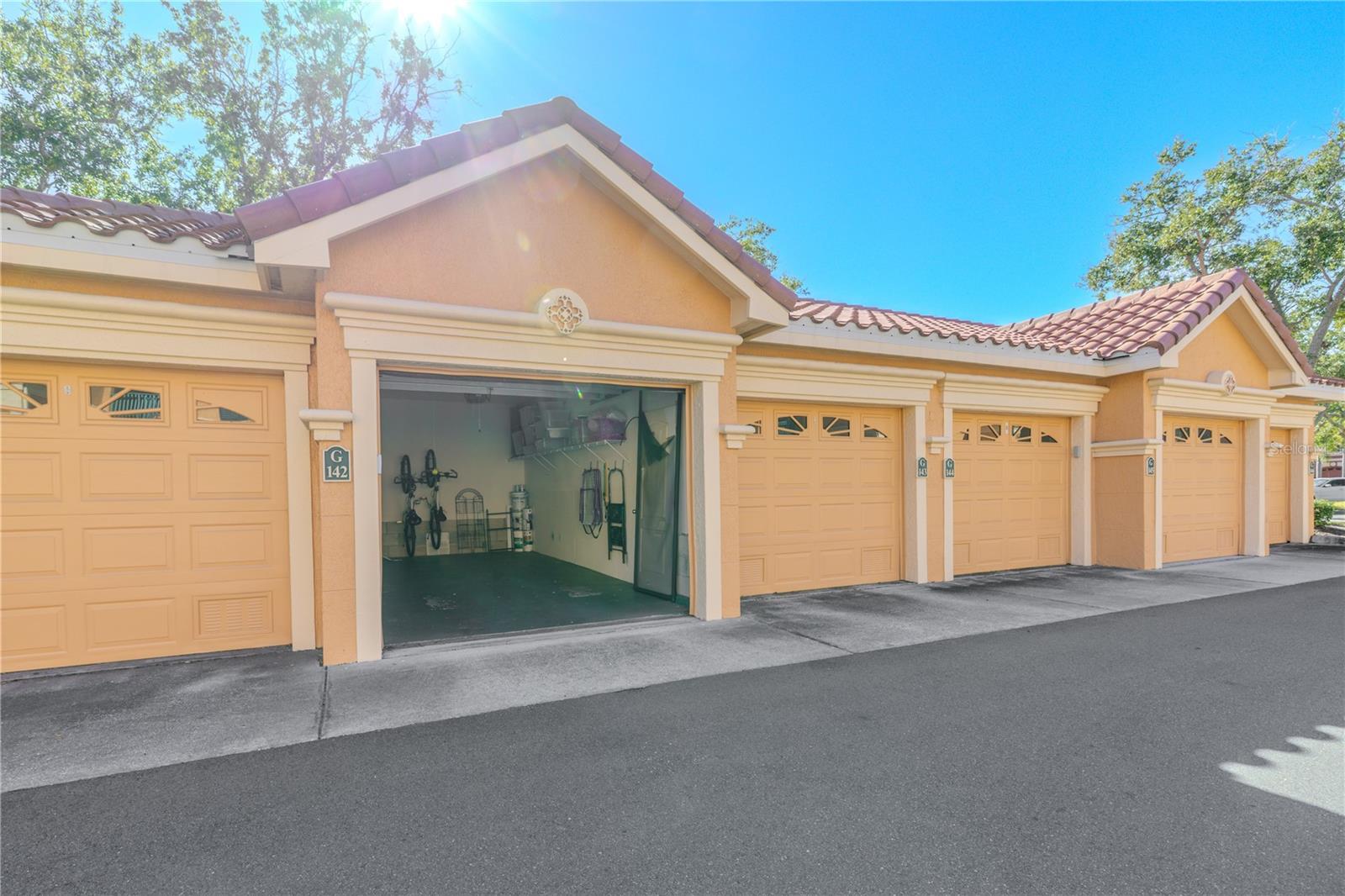 An elevated aerial view highlights the Mediterranean-style architecture of the Grand Bellagio community, showcasing tile-roofed buildings, palm-lined grounds, and the desirable corner placement of this residence within a beautifully maintained setting.