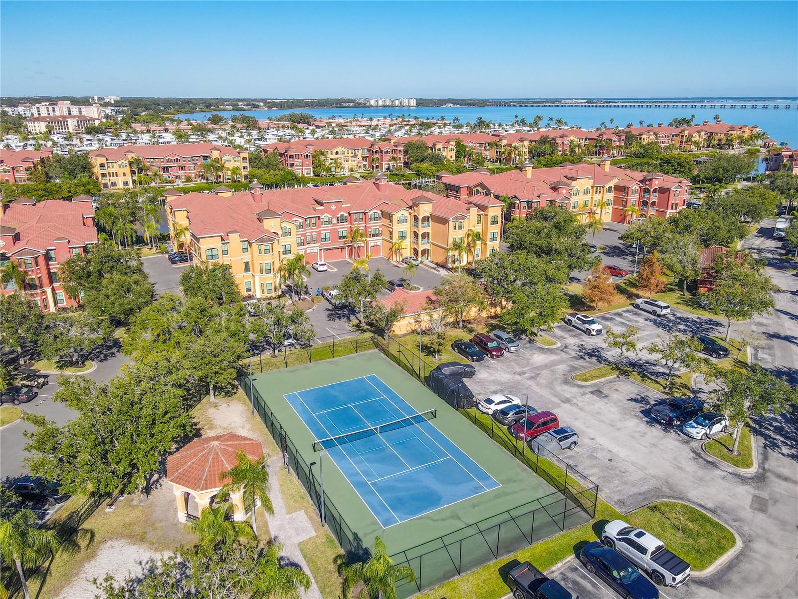 Sweeping aerial views showcase the vibrant Mediterranean-style community set against sparkling bay waters and an iconic bridge backdrop, capturing the essence of relaxed waterfront living.