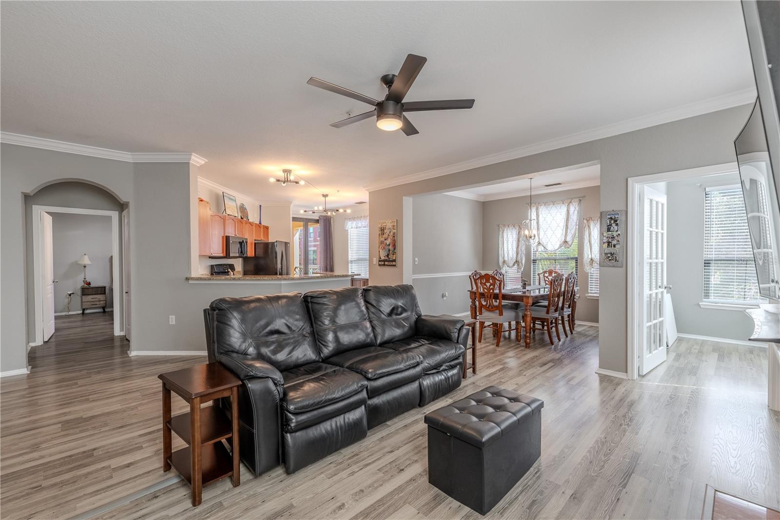 A bright, open kitchen features granite countertops, warm wood cabinetry, stainless appliances, modern lighting, and sliding glass doors that lead to the private balcony, seamlessly connecting indoor and outdoor living.