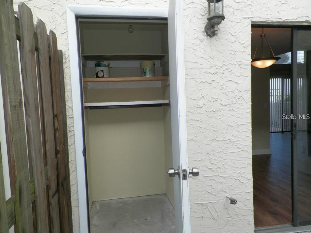 Fenced in patio rear of townhouse with storage closet