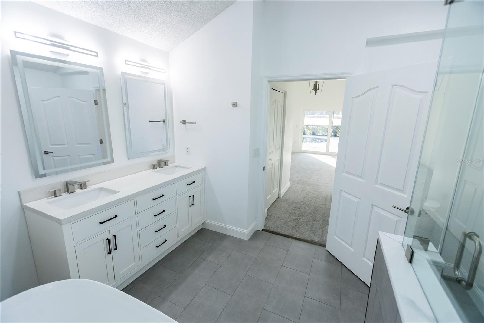Primary Bathroom Dual Sinks View into Primary Bedroom