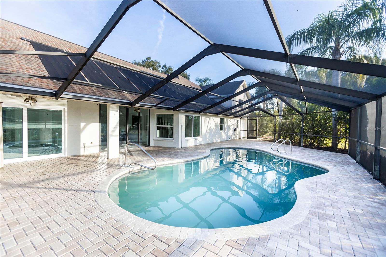 Pool, ceiling fans on deck, new screening on pool cage, door on either side of enclosure leading to yard, beautiful view from inside of home
