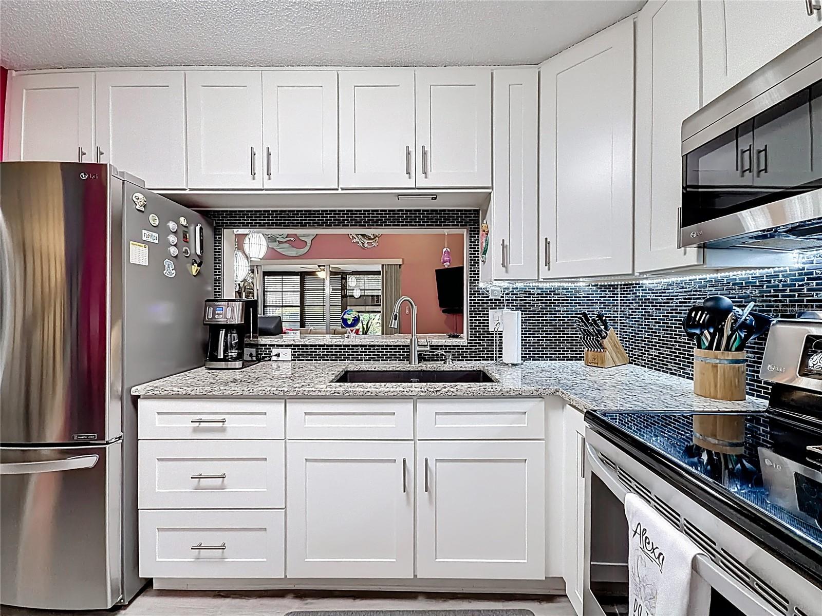 502 Bouth Ave - kitchen, white cabinets, granite counters, pass through to living area