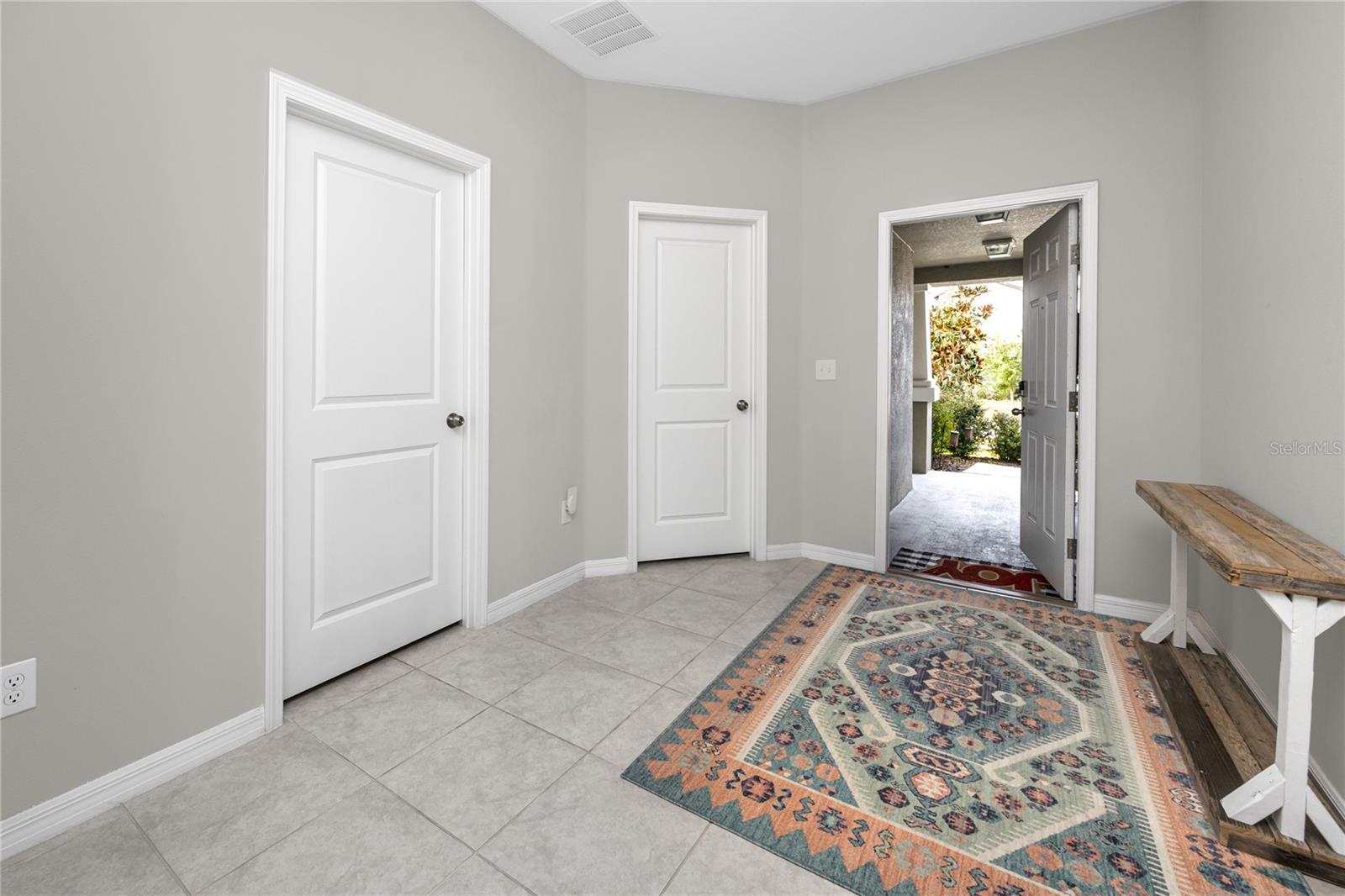 Large entryway with covered porch, two bedrooms and a bathroom at the front of the house.