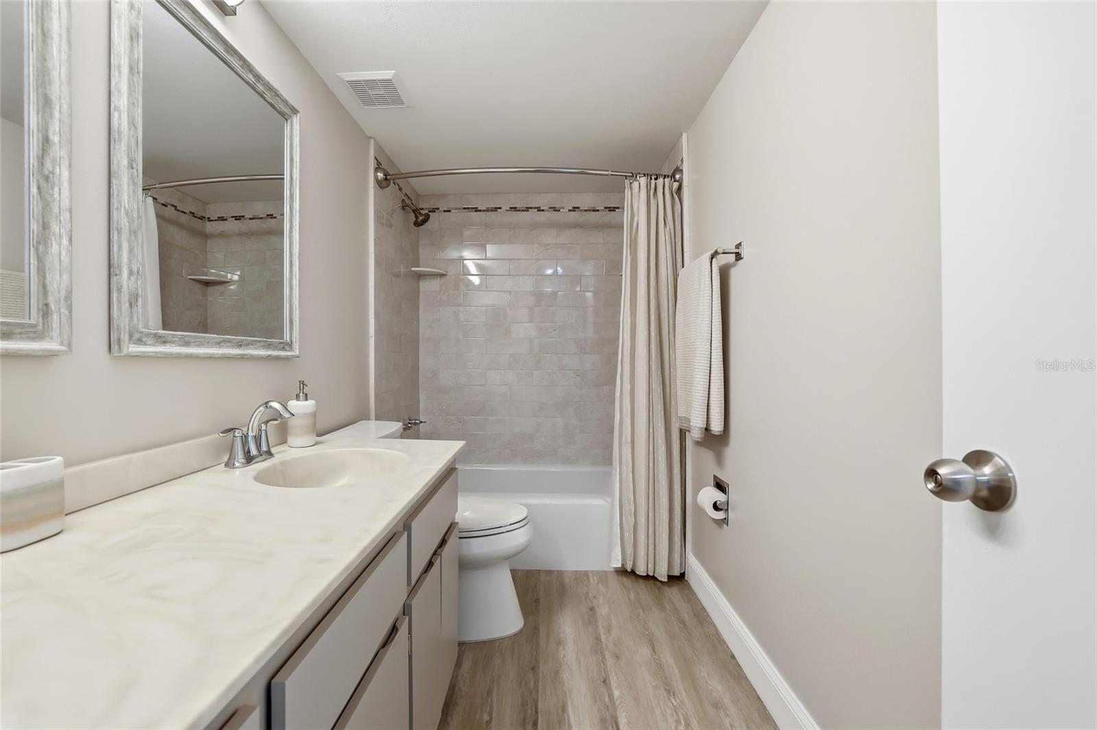 Primary bathroom features an updated shower and stylish vinyl plank flooring.