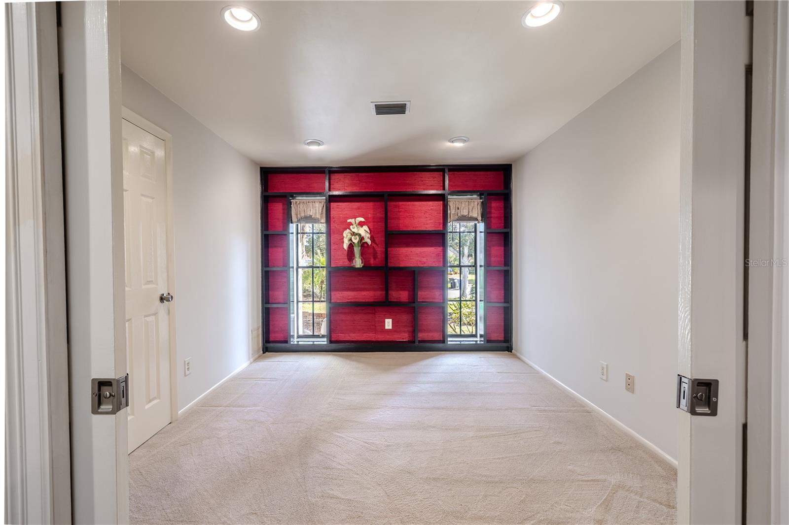 This versatile second bedroom, accessed through elegant pocket French doors, offers a seamless connection to the primary suite—ideal for a private sitting room, home office, or nursery—with soft natural light and a refined custom accent wall.