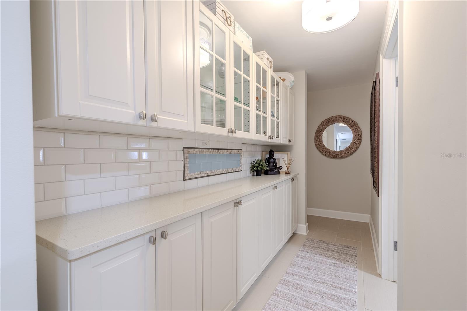This functional hall off the kitchen features floor-to-ceiling wood cabinetry, quartz counters, and the same large-format Italian tile flooring, providing seamless access to the garage and laundry room with abundant built-in storage.