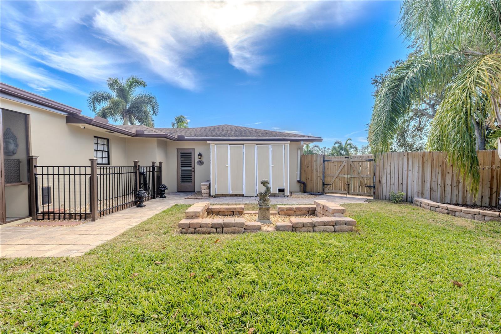 The fully fenced backyard includes dual storage sheds for added convenience, along with a paver walkway, dual gated access, and a grassy yard ideal for storage, hobbies, or outdoor enjoyment.